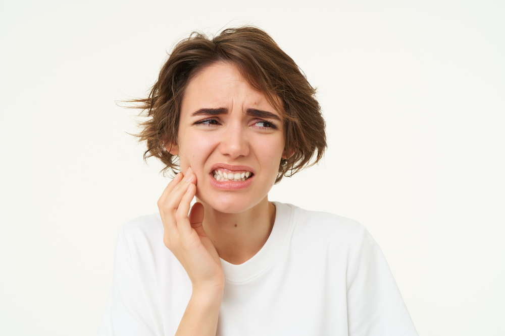 close-up-woman-has-toothache-touches-her-teeth-frowns-from-painful-discomfort-stands (1)